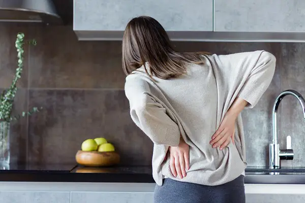 אישה במטבח הסובלת מכאבי גב תחתון